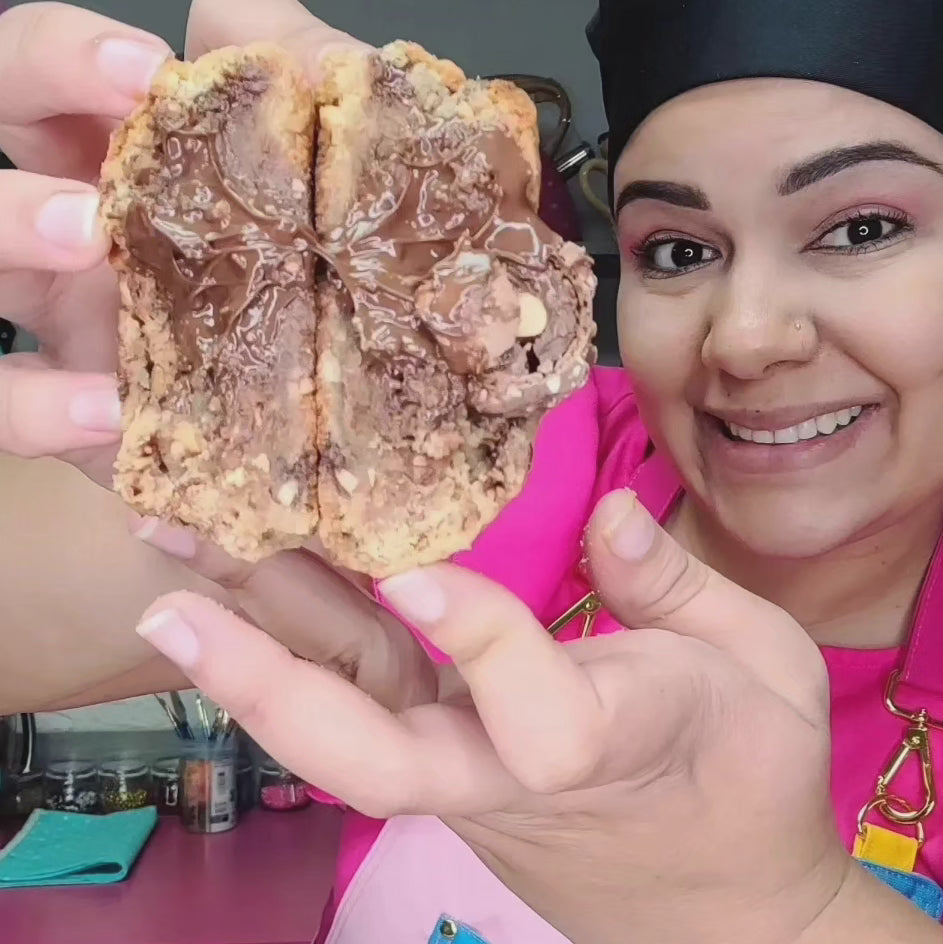 A baker holding a chocolate cookie.